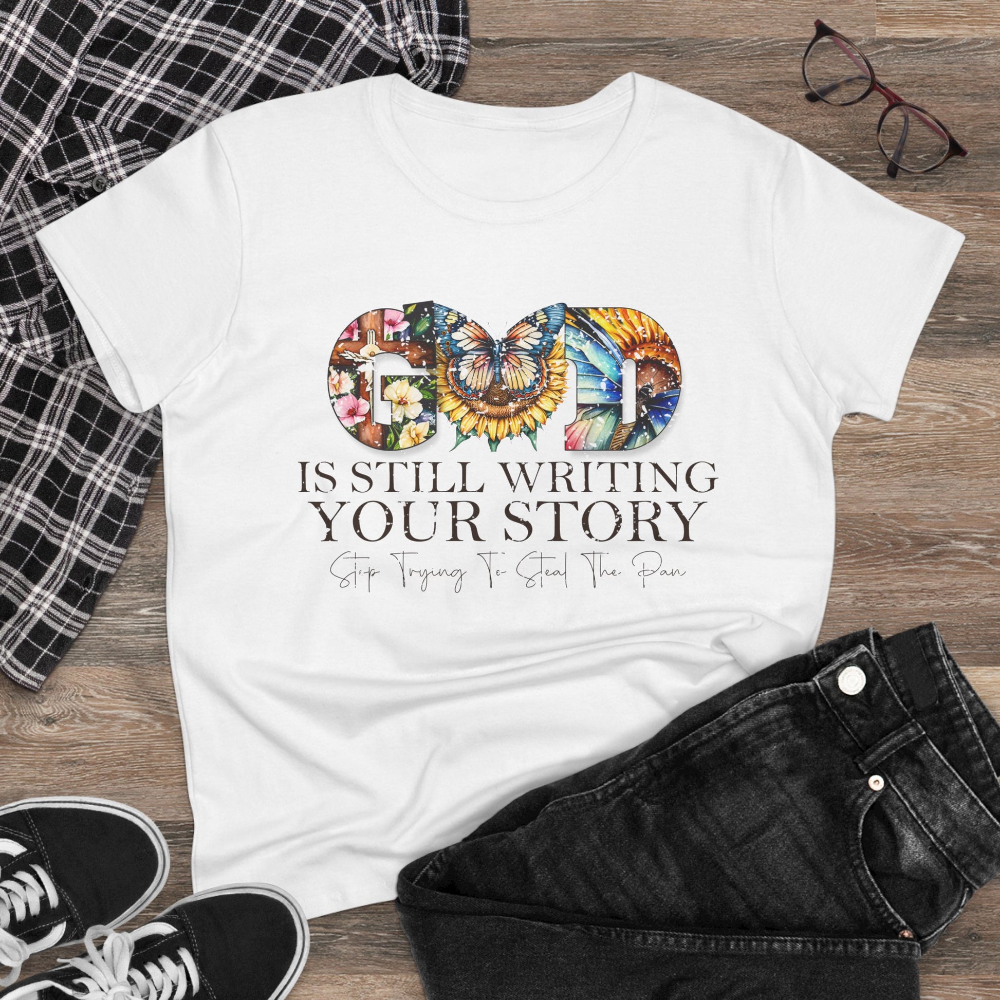 White t-shirt with motivational quote and colorful design on a wooden surface with casual items.